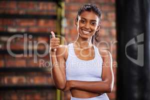 Working out makes me feel good, too. a sporty young woman showing thumbs up at the gym.