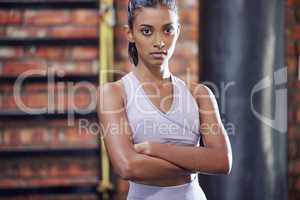 Being weak just doesnt suit me. Portrait of a sporty young woman standing with her arms crossed in a gym.