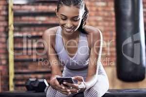 Catching a break between sets. a sporty young woman using a cellphone while taking a break in a gym.