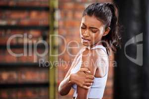 Sore muscles holding you back. a young woman suffering from an injury while at the gym.