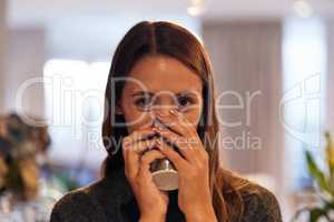 I cant function without my daily cup. Portrait of a young woman drinking a warm beverage at home.