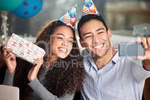 Birthdays spent with someone you love are special. two young businesspeople taking a selfie while celebrating a birthday at work.