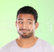 Dont look at me. a handsome young man making a face against a green background in studio.