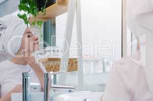 Always maintaining healthy skin. a young woman using a cotton swab to clean her face.