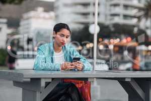 Edgy, sad and lonely woman texting on social media dating app on a phone and looking serious, depressed or bored outside in an urban city. A single girl posting about her bad emotional breakup online