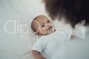 One baby, so many smiles. an adorable baby girl gazing at her mother on the bed at home.