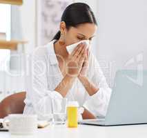 I promise Im not sick. a young businesswoman sitting at her desk blowing her nose in a modern office.