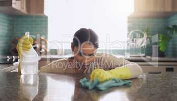 Its a great day to get the house spotless. a young woman scrubbing down her kitchen counter at home.