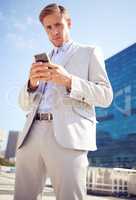Dressed to impress. a young businessman using a cellphone in the city.