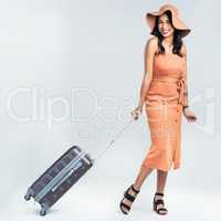 I have a desire to travel the world. Studio shot of a woman pulling her suitcase against a white background.