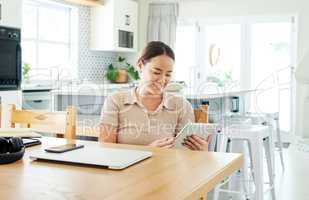 Ive almost completed my to-do list. an attractive young woman sitting alone and using a digital tablet to work from home.