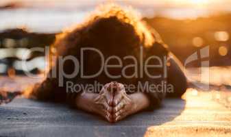 Reconnecting with the earths vibration through my yoga practice. an unrecognizable woman doing yoga alone on the beach at sunset.