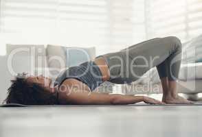Stronger glutes, here I come. an attractive young woman working out in her living room during the day.