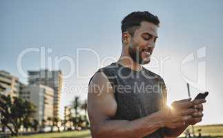Staying connected on his fitness journey. a sporty young man using a cellphone while exercising outdoors.