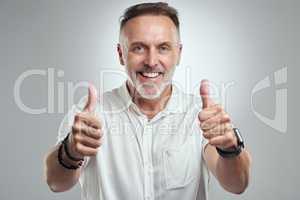 I am so damn proud of you. Studio portrait of a mature man showing thumbs up against a grey background.