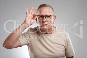 Hang on a minute... a handsome mature man standing alone against a grey background in the studio and adjusting his glasses.