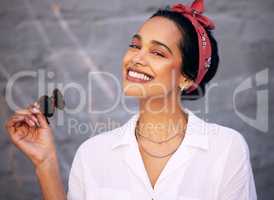 A smile is infectious. an attractive young woman standing alone against a grey wall outside and posing during the day.