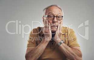 It cant be true. Studio shot of an elderly man in disbelief against a grey background.