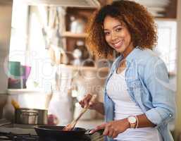 Whipping up something delicious just for you. Portrait of a happy young woman preparing a meal on the stove at home.