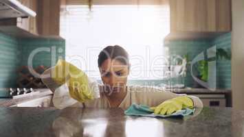 Its so satisfying to see a gleaming counter. a young woman scrubbing down her kitchen counter at home.