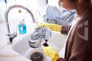 The sooner you do it, the less dishes you have to wash. a young woman washing the dishes at home.