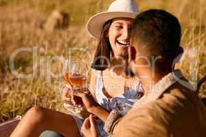 Good wine and good company. a young couple embracing one another on a date outside in nature.
