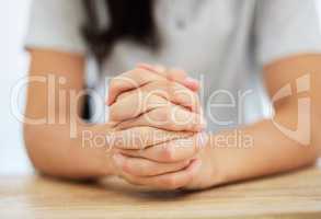 Always keeping the faith. an anonymous woman sitting at a table with her hands clasped together.