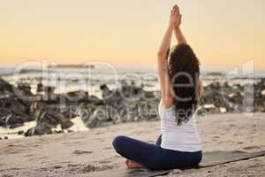 Nature is meditations super power. Rearview shot of an unrecognizable young woman practicing yoga on the beach.