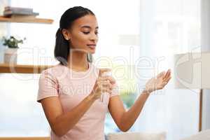 Dont forget to sanitise. a young woman sanitising her hands at home.