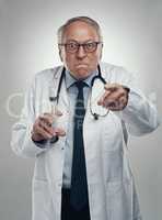 You have to have this injection. an elderly male doctor holding a syringe for injection in a studio against a grey background.