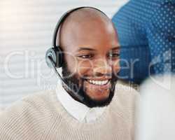 Solving each query with a smile. a handsome young salesman sitting in the office and wearing a headset.