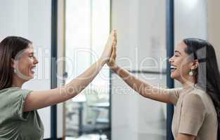 Teamwork allows us to achieve the best. two businesswomen giving each other a high five in an office.