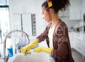 Because a dirty kitchen is a dirty house. a young woman washing the dishes at home.