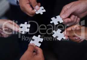 Working in a group takes less time. a group of businesspeople putting together puzzle pieces.
