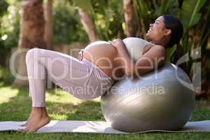 I want to feel fit and strong for delivery. a pregnant woman working out with a stability ball outside.
