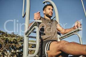 Spending some time out to build some muscle. Low angle shot of a muscular young man exercising at a calisthenics park.