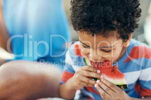 Mom always packs my favourite food. a young boy enjoying a piece of watermelon outside.