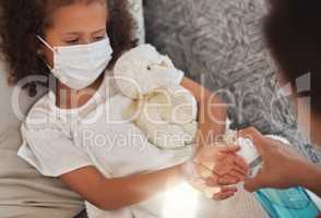 Cleaning hands with sanitizer during covid, caring mother showing good hygiene habits for sick child. Close up of a parent taking care of an unwell daughter during the coronavirus pandemic.
