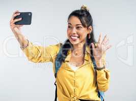 Collect moments not things. Studio shot of a woman wearing a backpack and taking selfies against a white background.