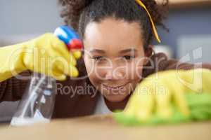 Sorry germs, you chose the wrong house. a woman wearing gloves and holding a spray bottle while cleaning a wooden surface at home.