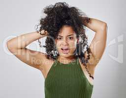 How am I suppose to manage this much hair. Studio shot of a woman with messy hair posing against a grey background.