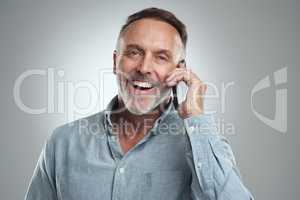 Thats just the news I wanted to hear. Studio portrait of a mature man talking on a cellphone against a grey background.