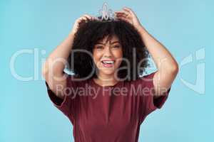 Whats a queen without her king Even more powerful. Studio shot of a young woman putting a crown her head against a blue background.