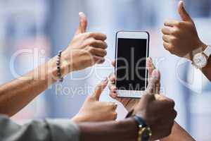 This app is worth downloading. Closeup shot of a group of unrecognisable businesspeople showing thumbs up around a cellphone with a blank screen.