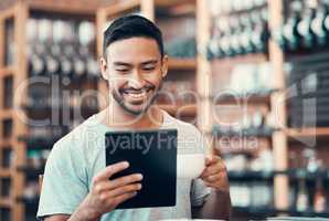 Happy, relaxed and carefree man reading social media news on a tablet while enjoying coffee. Young casual guy replying to emails, browsing the internet or subscribing to online dating app at a cafe