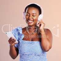 Creativity flourishes in solitude. Studio shot of a young woman using a smartphone and headphones against a pink background.