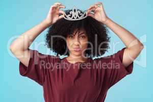 Fix your crown, never let it fall. Studio shot of a young woman putting a crown her head against a blue background.