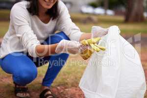 Blissful the world ,if everyone swept their own porch first. Closeup shot of a woman picking up trash in a park.