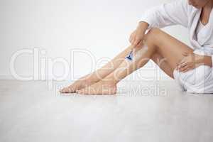 Hair be gone. an unrecognizable woman sitting down and shaving her legs at home.