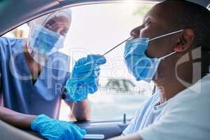 Doctor or nurse doing covid or corona virus test at a drive thru on a man sitting in a car. Medical professional taking nose swab sample from male patient through window with a PCR diagnostic kit.